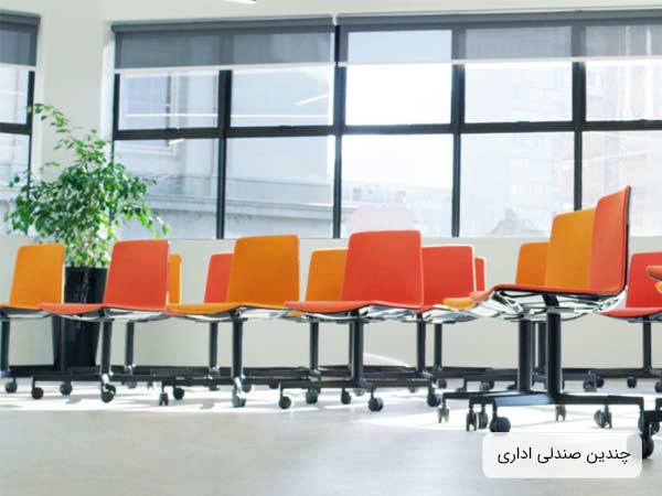 تعدادي صندلي چرخ دار مخصوص فضاهاي اداري و دفاتر کار به رنگ هاي نارنجي پررنگ و کمرنگ که در يک اداره قرار گرفته اند