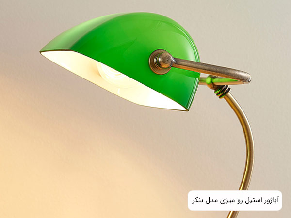 تصوير آباژور مدل بنکر با قاب شيشه اي سبز رنگ که لامپ ان روشن شده است.