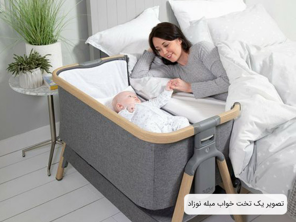 عکس يک تخت مبله برای نوزاد که در کنار يک تخت خواب قرار داده شده و يک کودک درون تخت نوزاد قرار گرفته است.
