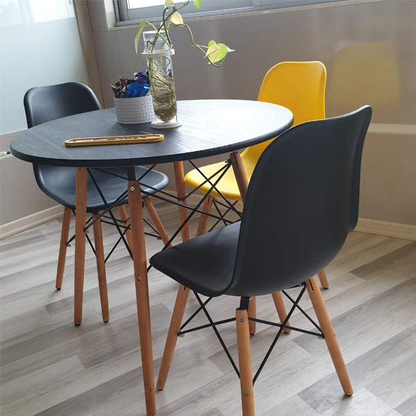 ميز و صندلی ناهار خوری گرد به رنگ مشکی و يک عدد صندلی زرد رنگ که در کنار این میز قرار گرفته است.