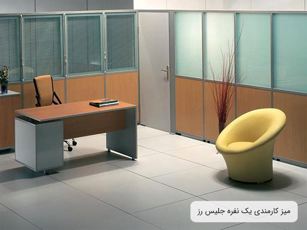 ميز کارمندی جليس مدل رز با طراحی مدرن و ساده در کنار يک صندلی اداری و در يک دفتر کار امروزی.