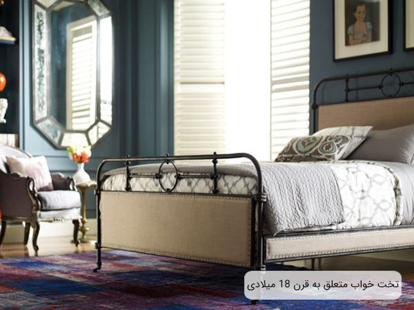 تصويری از يک تختخواب شيک و ساده با فريم فلزی و پارچه کرمي رنگ که يک دست خوشخواب روي آن قرار گرفته است.