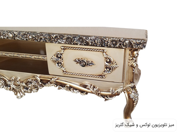 میز تلویزیون مدل گلریز با طراحی کلاسيک و منبت کاری به رنگ طلايی در پس زمينه سفيد.