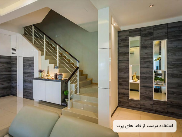 دکوراسيون مدرن يک اتاق نشيمن با مبلمان طوسي رنگ و استفاده بهينه از فضاي کنار پنجره با قرار دادن مبل در آنجا.