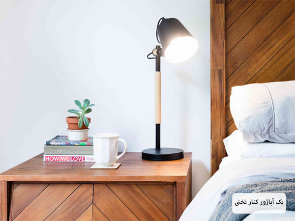 یک آباژور مدرن روی یک میز کنار تختی.