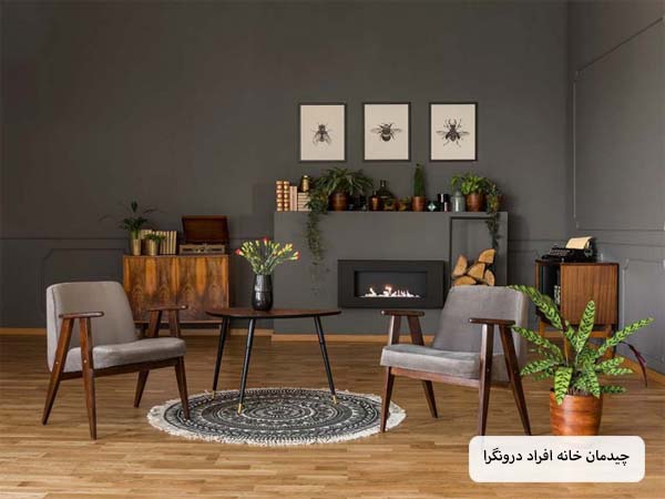 اتاق نشیمن یک فرد درونگرا با دیوار ها و مبلمانی به رنگ نوک مدادی تیره و صندلی هایی که با فاصله از هم قرار گرفته اند.